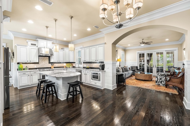 kitchen featuring a kitchen bar, a center island, hanging light fixtures, white cabinets, and dark hardwood / wood-style floors