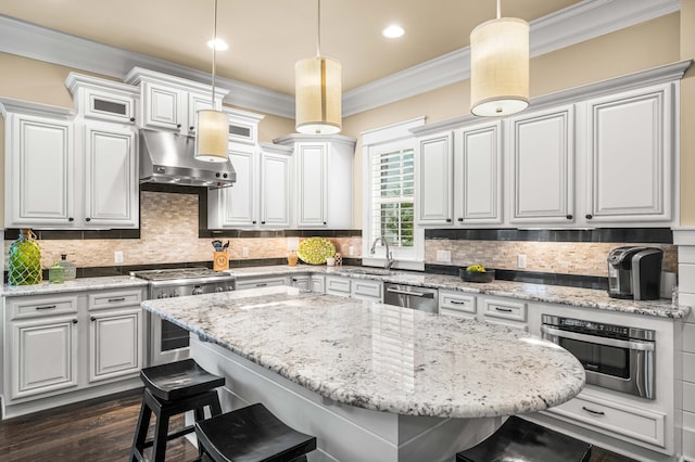 kitchen with white cabinetry, decorative light fixtures, stainless steel appliances, and a breakfast bar area