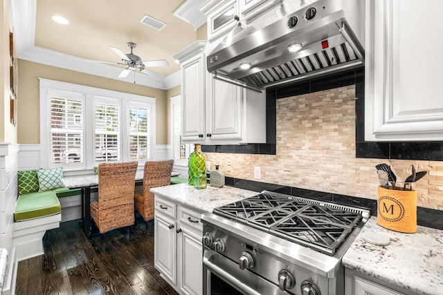 kitchen with dark hardwood / wood-style flooring, high end stainless steel range, white cabinets, crown molding, and exhaust hood