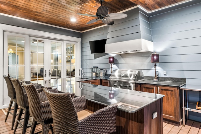 kitchen with sink, wooden walls, wood ceiling, and light hardwood / wood-style floors