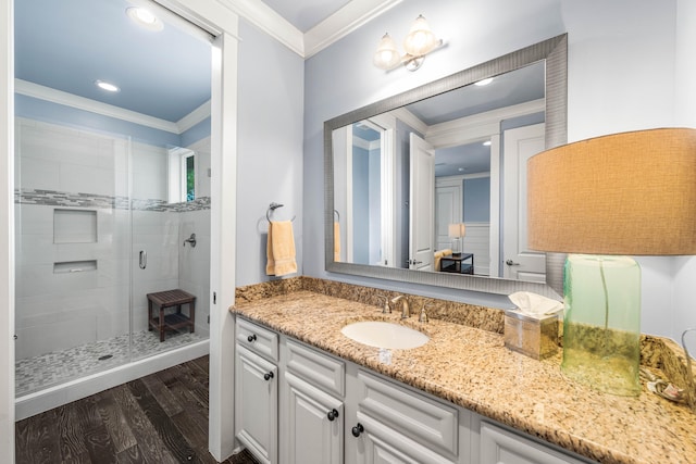 bathroom featuring vanity, crown molding, wood-type flooring, and a shower with shower door