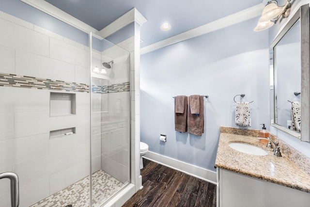 bathroom with a shower with door, toilet, ornamental molding, hardwood / wood-style floors, and vanity