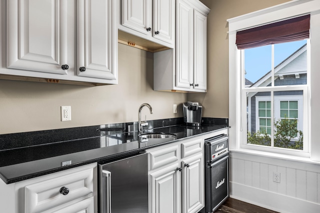 kitchen featuring sink, white cabinetry, a healthy amount of sunlight, and stainless steel refrigerator