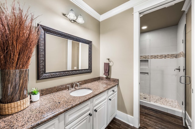 bathroom with vanity, ornamental molding, hardwood / wood-style flooring, and a shower with shower door