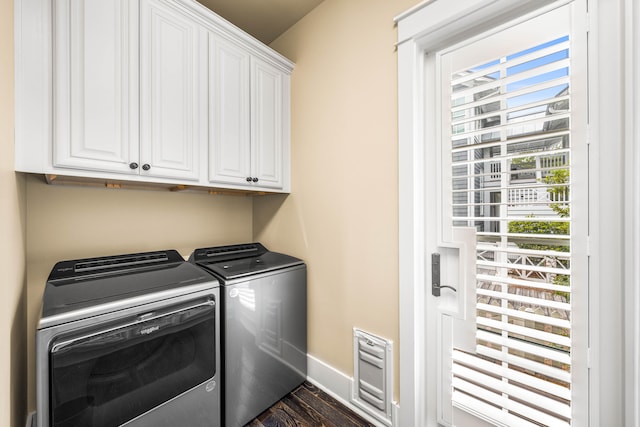 laundry room with cabinets, washing machine and clothes dryer, and dark hardwood / wood-style flooring