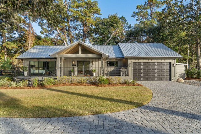 single story home featuring covered porch, a garage, and a front yard