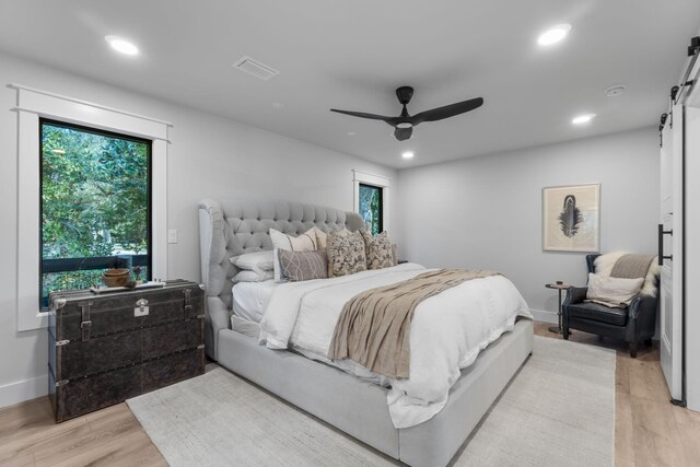 bedroom featuring light hardwood / wood-style floors, ceiling fan, and multiple windows