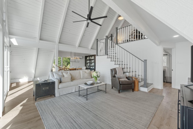 living room with ceiling fan, beamed ceiling, light wood-type flooring, and high vaulted ceiling