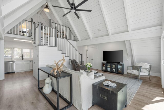 living room with high vaulted ceiling, light hardwood / wood-style floors, wood walls, and ceiling fan
