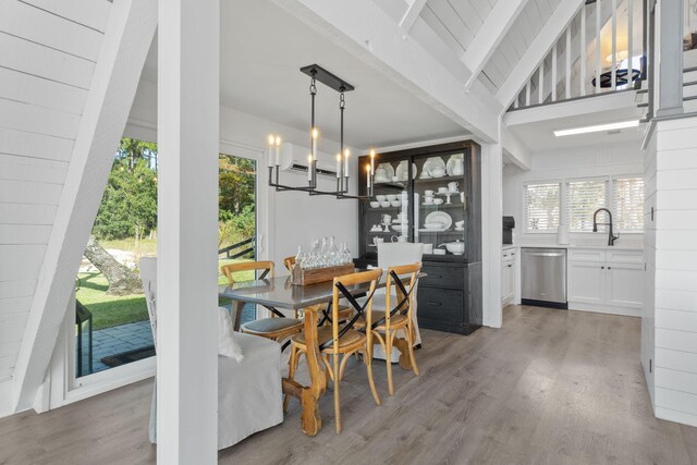 dining room with wood-type flooring, sink, lofted ceiling with beams, and a notable chandelier