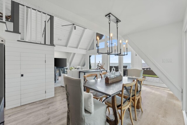 dining area featuring lofted ceiling with beams, light hardwood / wood-style floors, and a healthy amount of sunlight