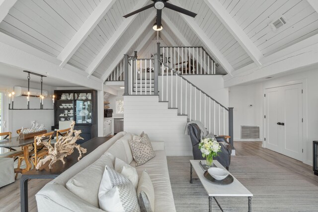 living room with high vaulted ceiling, wood walls, beamed ceiling, and light wood-type flooring