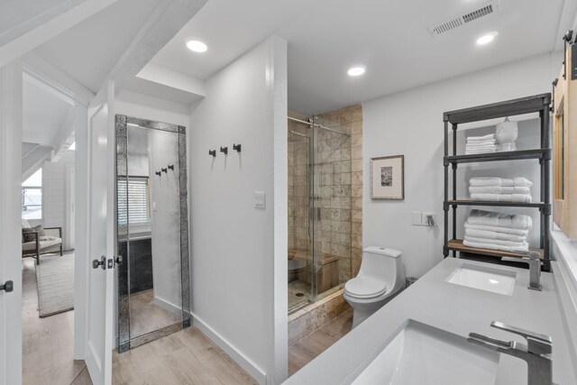 bathroom with hardwood / wood-style floors, walk in shower, sink, and toilet