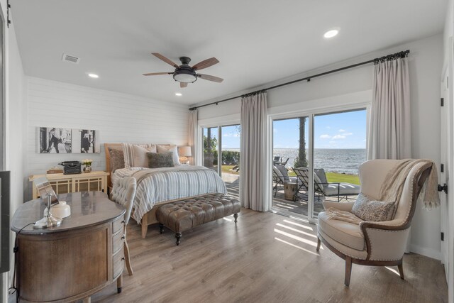 bedroom with light wood-type flooring, ceiling fan, access to exterior, and a water view