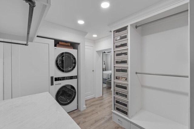 laundry area with stacked washer / dryer and light hardwood / wood-style floors