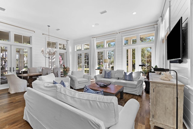 living room featuring dark hardwood / wood-style flooring, crown molding, french doors, and an inviting chandelier