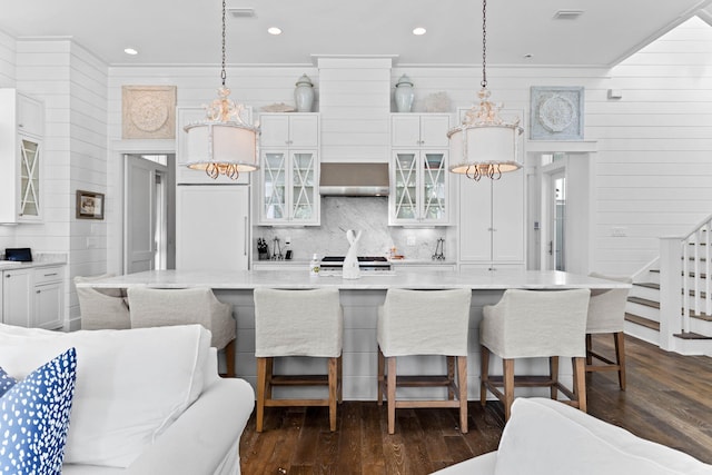 kitchen featuring a large island, a kitchen breakfast bar, dark hardwood / wood-style flooring, decorative light fixtures, and white cabinets