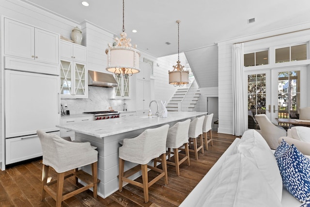 dining area featuring french doors, dark wood-type flooring, crown molding, wooden walls, and sink