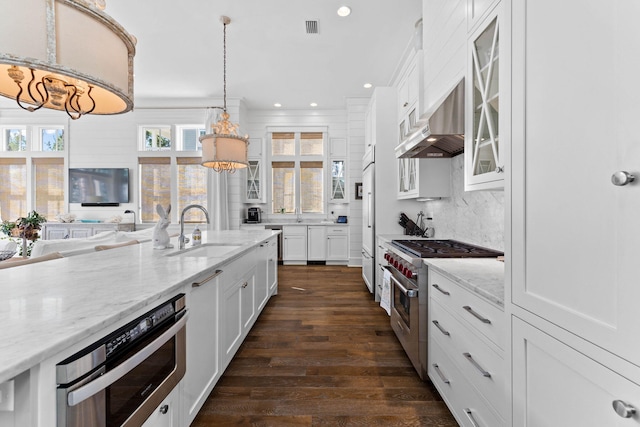 kitchen with hanging light fixtures, premium appliances, dark hardwood / wood-style floors, white cabinets, and exhaust hood