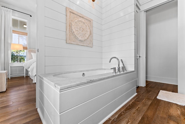 bathroom featuring a tub to relax in, hardwood / wood-style flooring, and wood walls