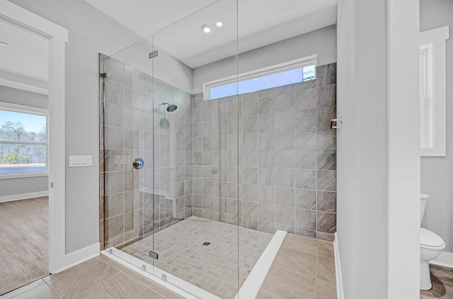 bathroom with toilet, hardwood / wood-style floors, a healthy amount of sunlight, and a shower with shower door