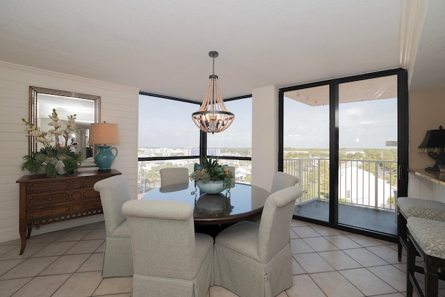 tiled dining space featuring a notable chandelier, wood walls, and floor to ceiling windows