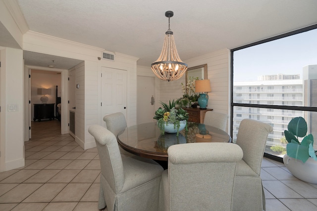 dining room featuring crown molding, light tile patterned flooring, a textured ceiling, and an inviting chandelier