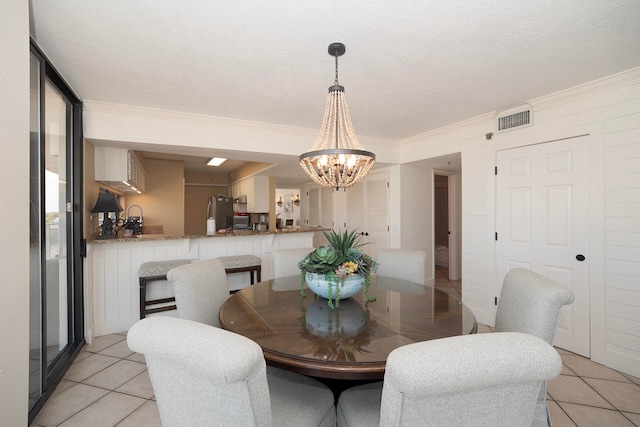 tiled dining room with a textured ceiling, an inviting chandelier, and ornamental molding