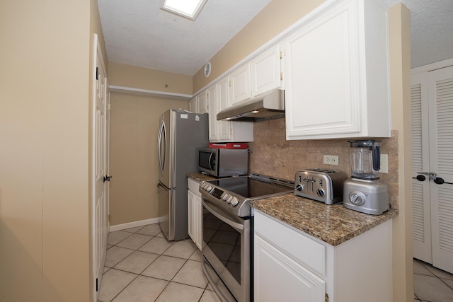 kitchen with decorative backsplash, white cabinetry, under cabinet range hood, stainless steel appliances, and light tile patterned flooring
