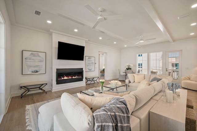 living room featuring ornamental molding, beamed ceiling, light wood-type flooring, and ceiling fan