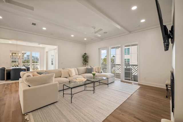 living room with beam ceiling, hardwood / wood-style flooring, plenty of natural light, and ceiling fan with notable chandelier