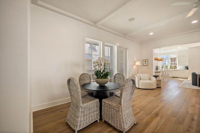 dining area featuring beam ceiling, wood-type flooring, and ceiling fan