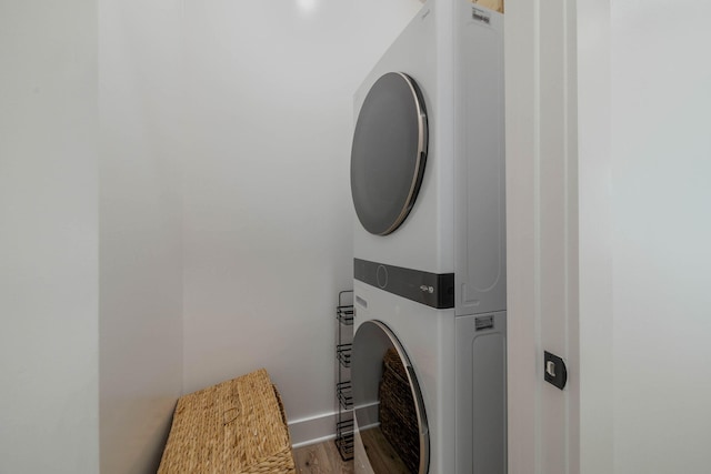 laundry room featuring hardwood / wood-style floors and stacked washer and dryer