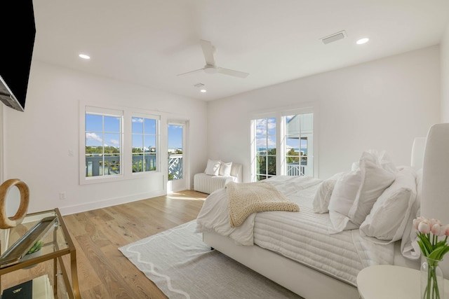 bedroom with light hardwood / wood-style flooring, ceiling fan, multiple windows, and access to exterior