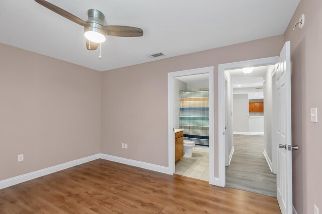 unfurnished bedroom featuring wood-type flooring, ensuite bath, and ceiling fan