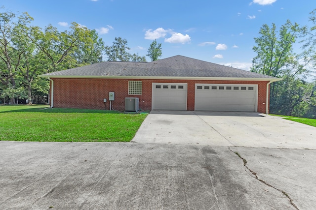 exterior space with a garage, cooling unit, and a lawn