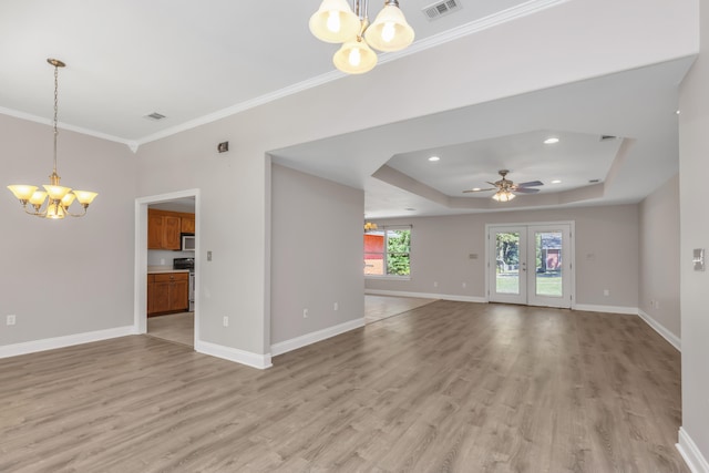 spare room with a raised ceiling, crown molding, light hardwood / wood-style flooring, and ceiling fan with notable chandelier