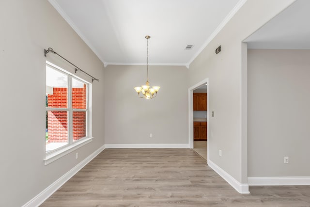 spare room featuring light hardwood / wood-style floors, crown molding, a healthy amount of sunlight, and a notable chandelier