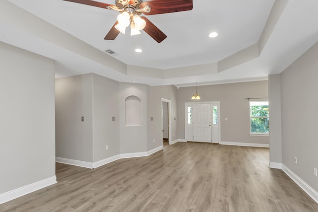 interior space featuring ceiling fan, a raised ceiling, and light hardwood / wood-style flooring