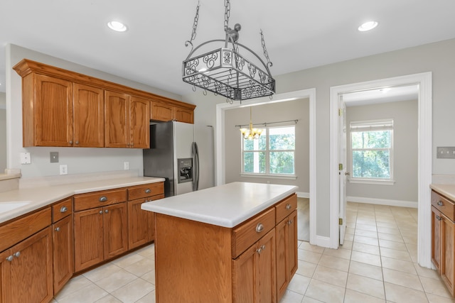 kitchen with a center island, hanging light fixtures, a notable chandelier, stainless steel fridge, and light tile patterned floors