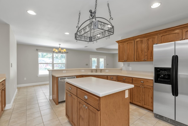 kitchen with appliances with stainless steel finishes, a center island, a notable chandelier, and pendant lighting