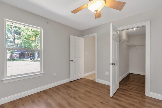 unfurnished bedroom featuring hardwood / wood-style floors, ceiling fan, a closet, and multiple windows