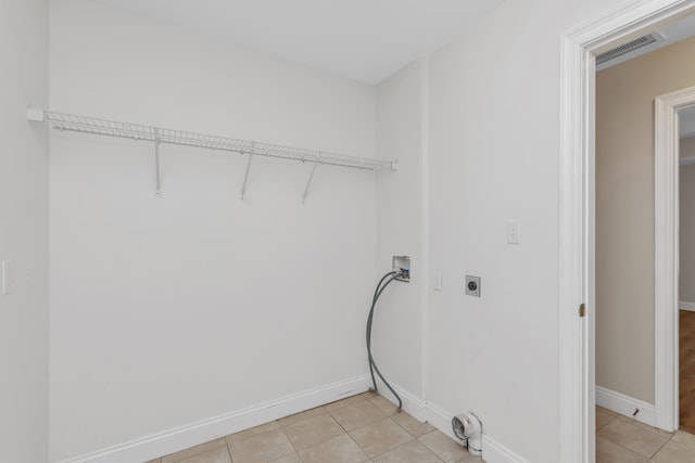 clothes washing area with electric dryer hookup, hookup for a washing machine, and light tile patterned floors