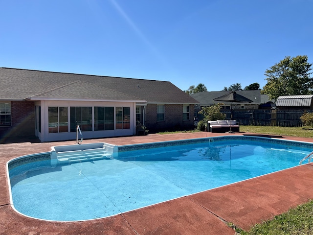 view of swimming pool with a sunroom, a patio, fence, and a fenced in pool