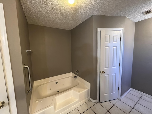 full bath with tile patterned flooring, a whirlpool tub, a textured ceiling, and baseboards