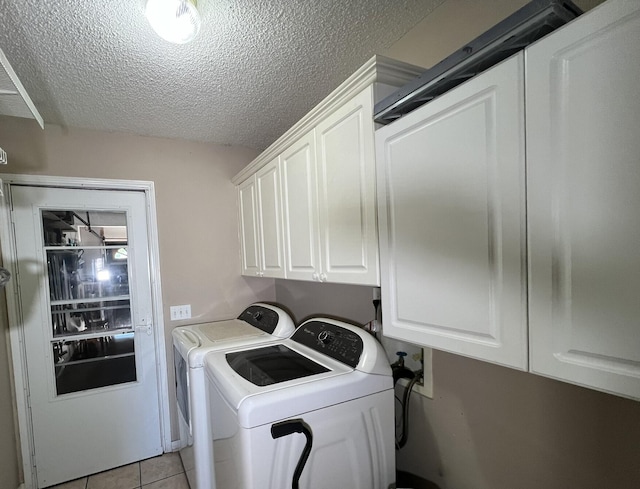 washroom featuring washer and dryer, light tile patterned floors, cabinets, and a textured ceiling