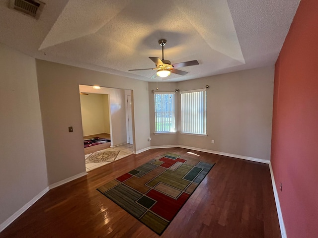 unfurnished room with ceiling fan, dark hardwood / wood-style flooring, and a textured ceiling