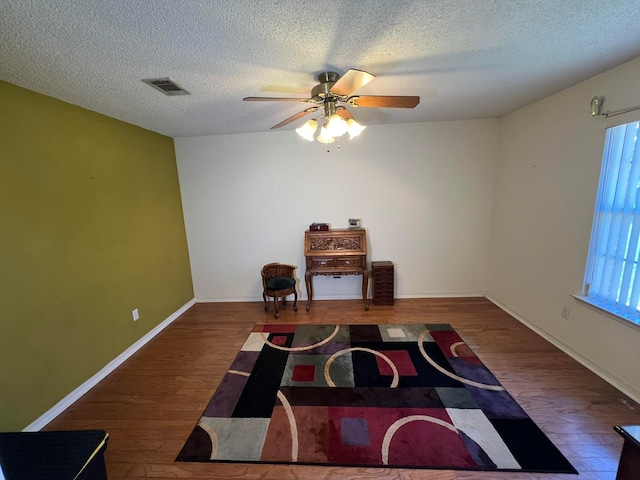 sitting room with ceiling fan, dark hardwood / wood-style flooring, and a textured ceiling