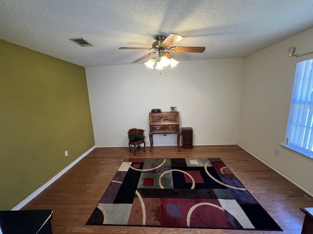 sitting room featuring a textured ceiling, baseboards, visible vents, ceiling fan, and wood finished floors