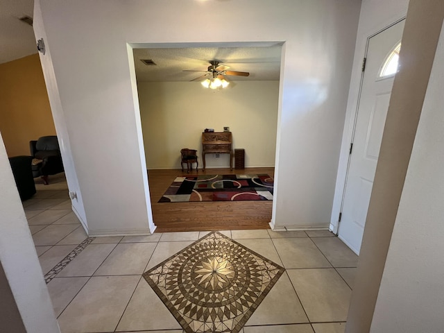 hall featuring light tile patterned floors, baseboards, and visible vents
